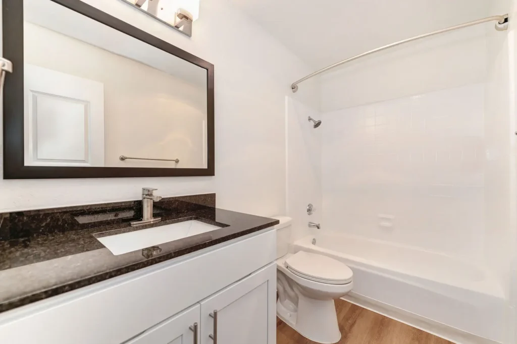 Bathroom with tub shower, toilet, and granite countertops