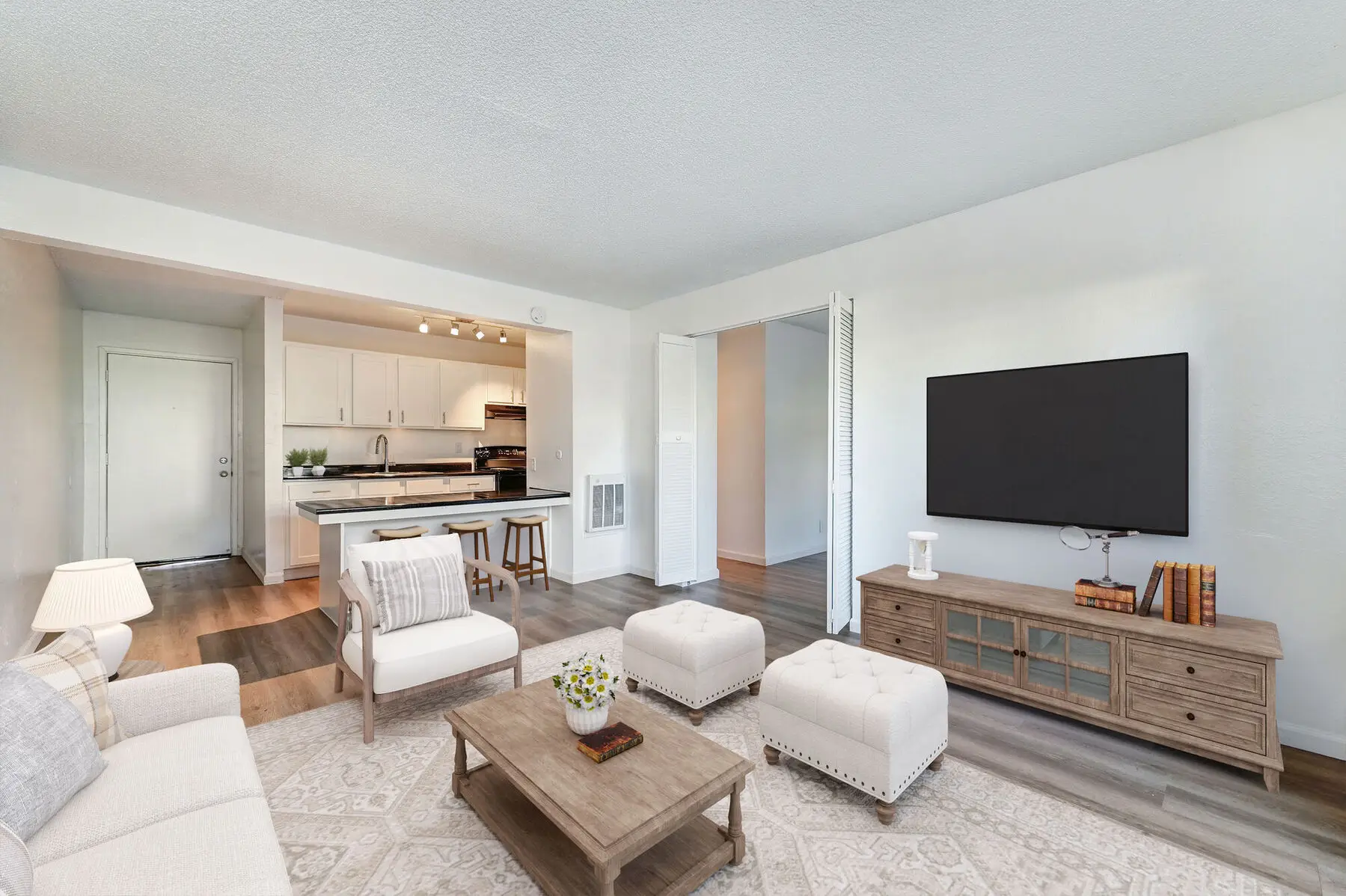 Staged model living room with view of breakfast bar and kitchen