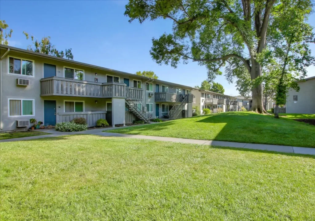 Building exteriors with balconies and patios, lots of trees and paths