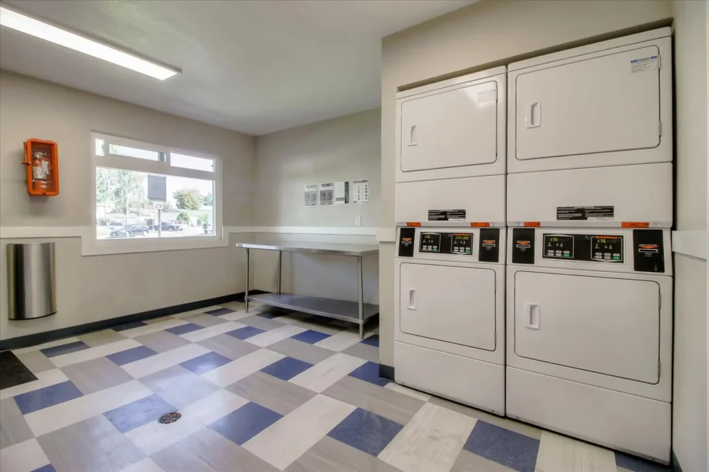 Laundry building interior with several washer and dryer units and a folding table