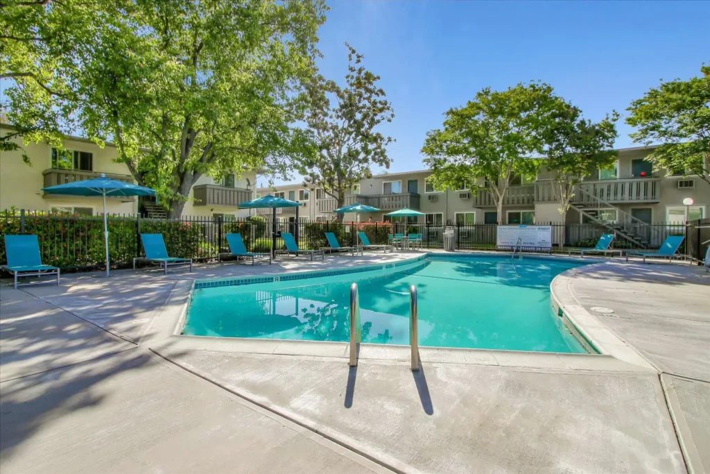 Fenced pool deck with covered and uncovered seating, large trees