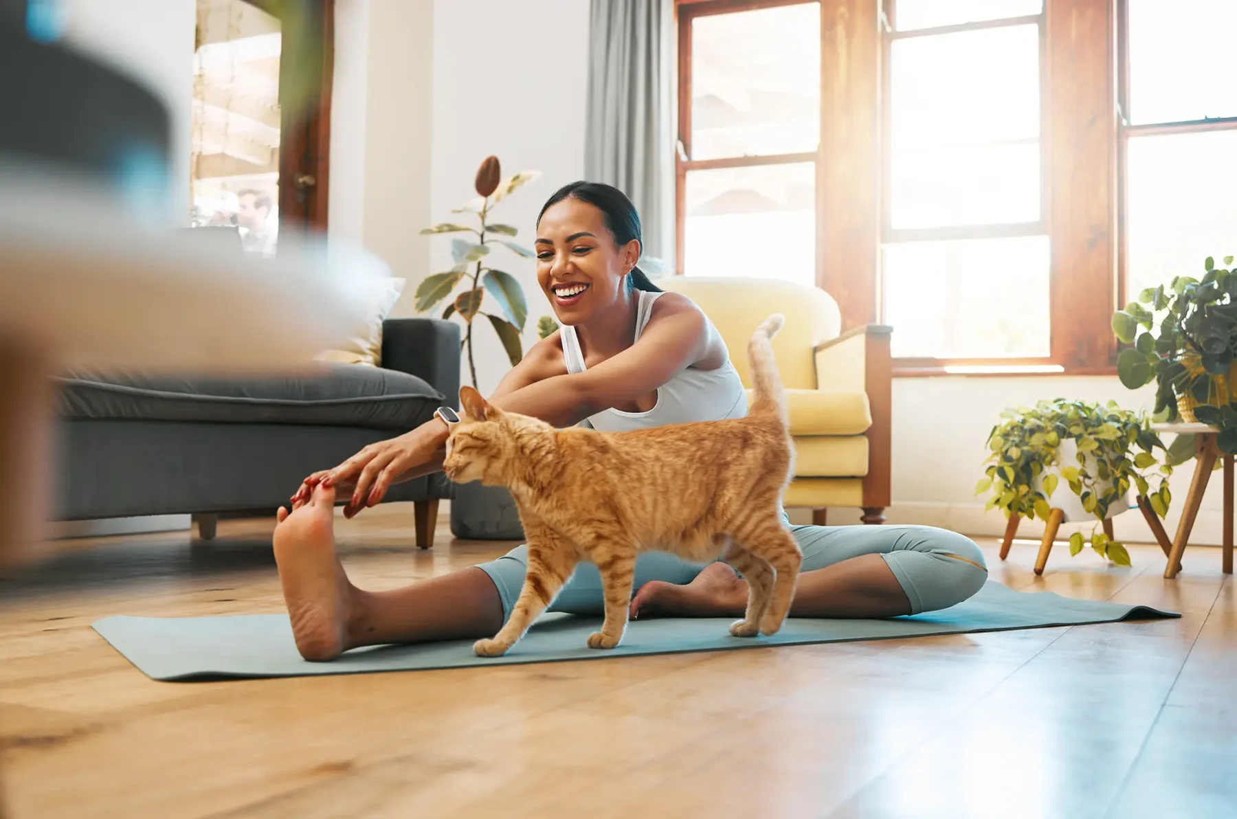 Woman doing yoga in the living room with a cat on the floor next to her